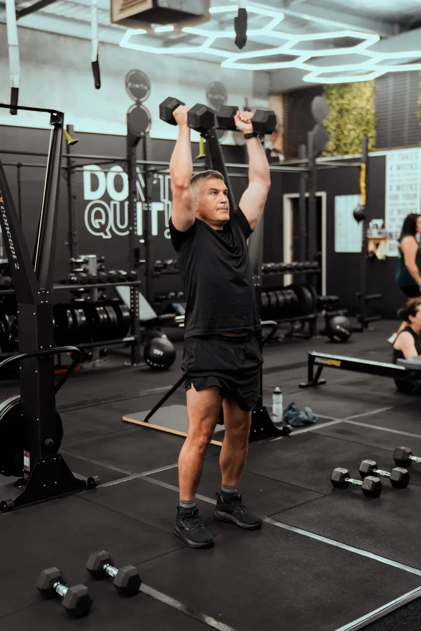 Member pressing dumbbells overhead