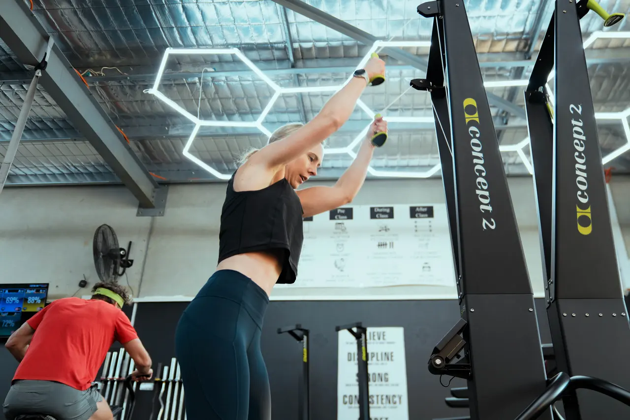 Member on the ski erg beneath the studio lighting